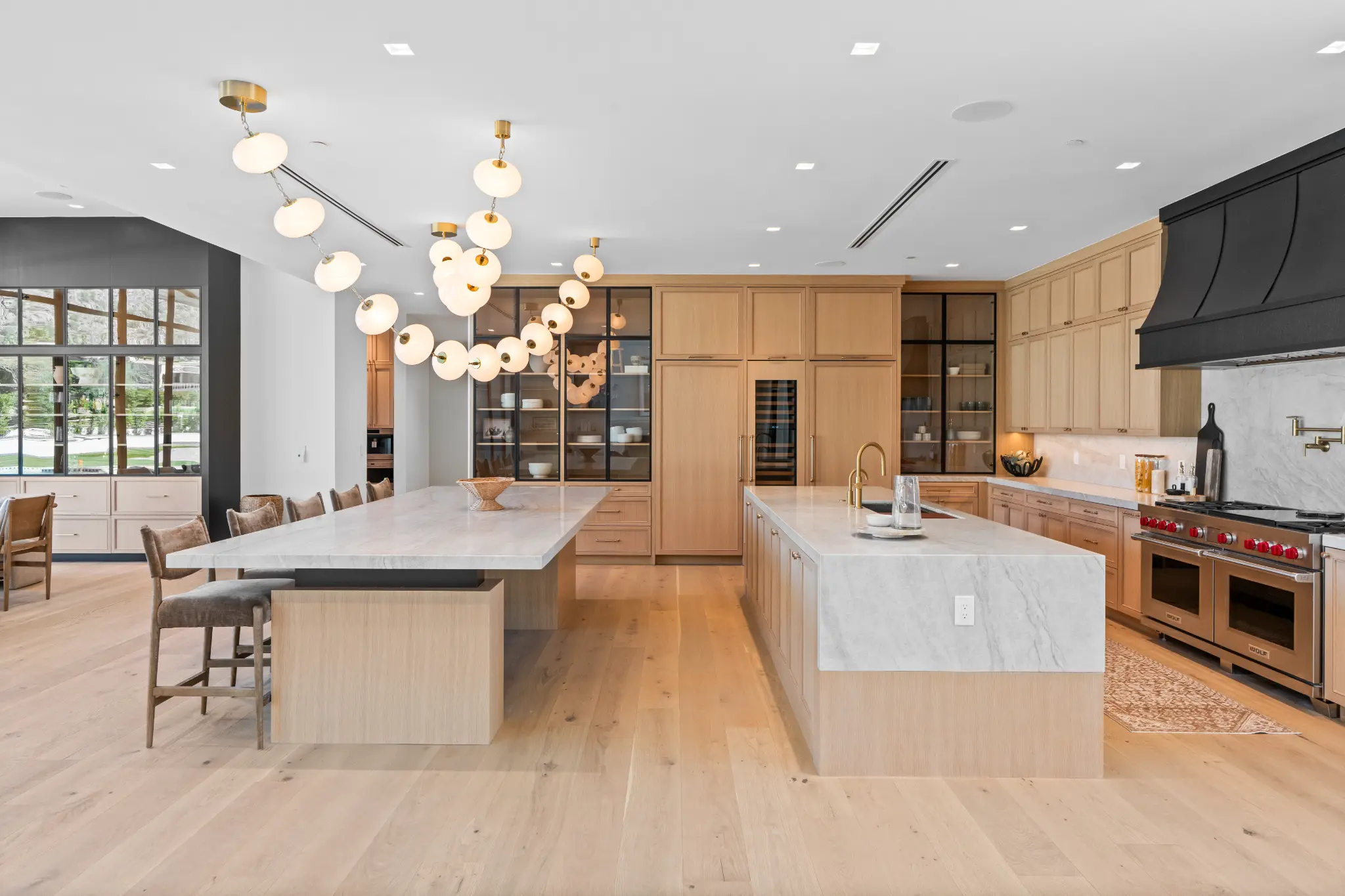Luxury kitchen with dual islands, marble countertops, custom cabinetry, and professional range