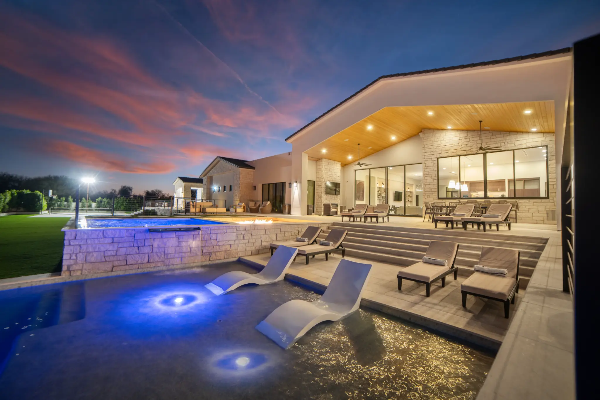 Resort-style pool with in-water chaise lounges, fire feature, and covered outdoor living pavilion